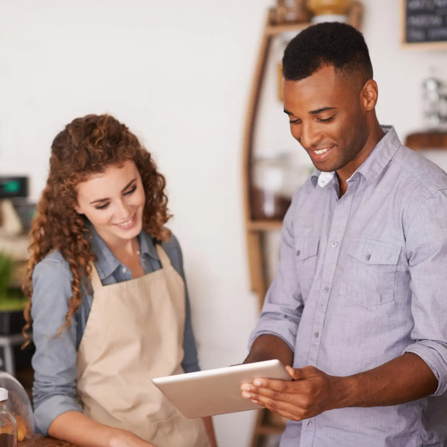 Small business owner and employee reviewing a Facebook Ads strategy on a tablet, highlighting digital marketing for local businesses.