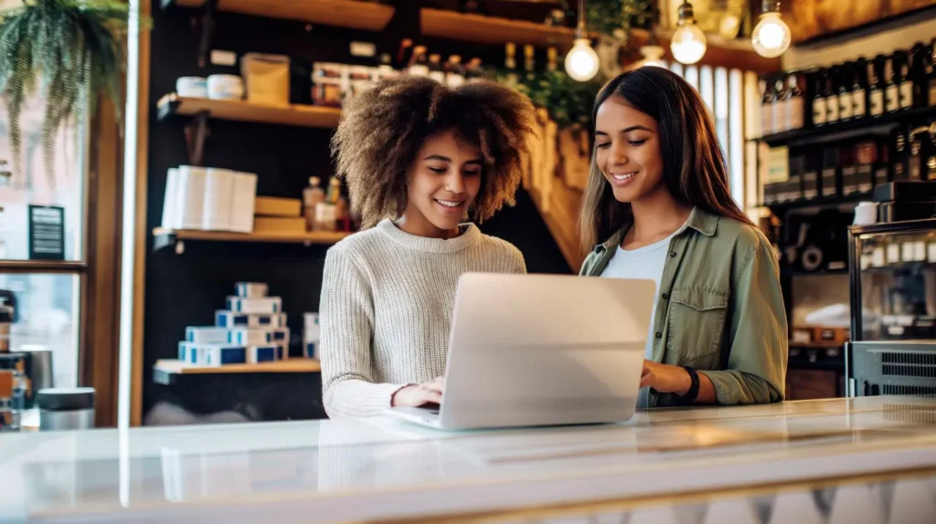 Dos emprendedoras jóvenes gestionando su negocio en una tienda con la ayuda de un CRM en una laptop, destacando el mejor CRM para pymes.