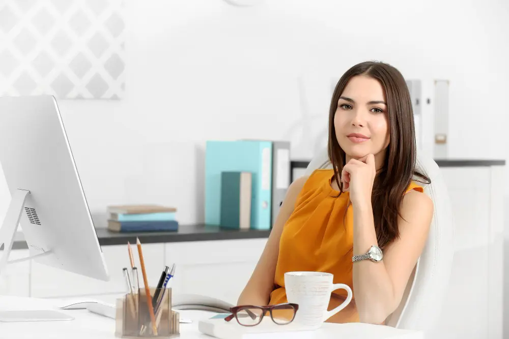 Empresaria en su oficina, pensando en estrategias CRM para pymes, mientras trabaja frente a su computadora.