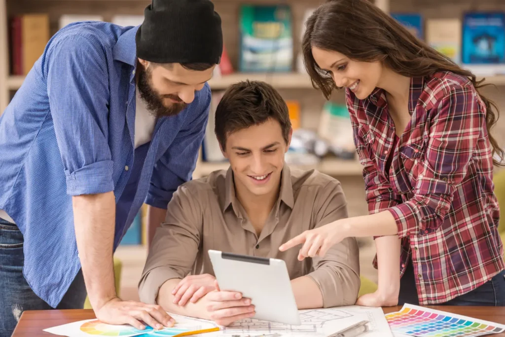 Grupo de jóvenes profesionales en una agencia de marketing digital colaborando en una estrategia en tablet, rodeados de gráficos y colores, representando la mejor agencia de marketing digital.