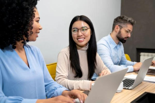 Equipo en reunión usando un CRM para equipos de venta desde portátiles en oficina