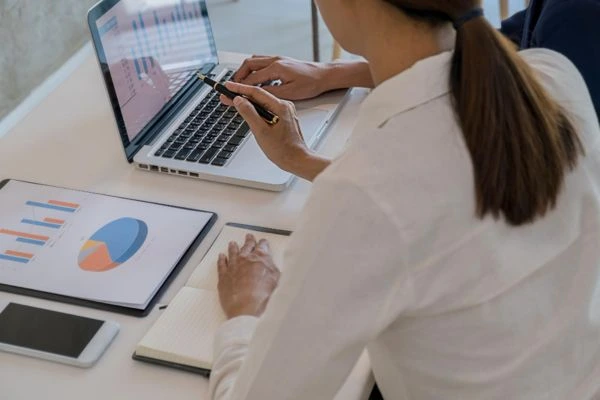 Profesional revisando dashboard de CRM y automatización en laptop con gráficos y reporte en tablet