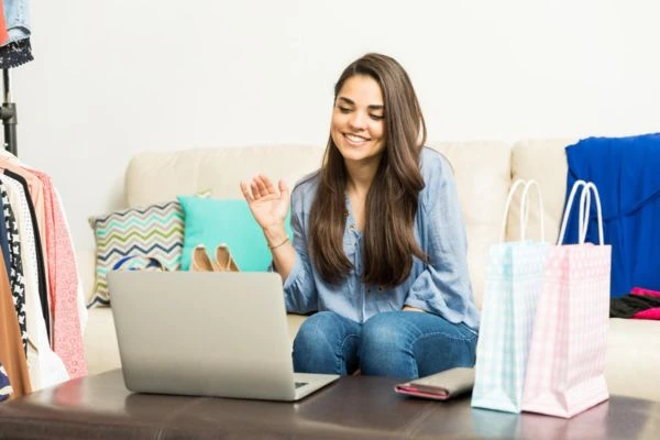 Mujer comprando en línea con bolsas y ropa junto al portátil - campañas de remarketing en Meta Ads para impulsar las ventas