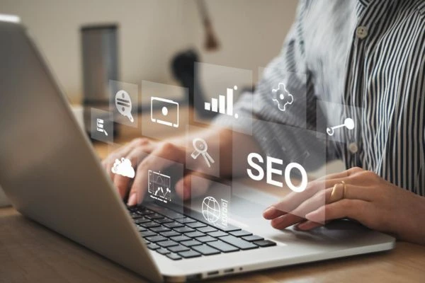Profesional trabajando en portátil con iconos de SEO y analítica digital sobre la pantalla