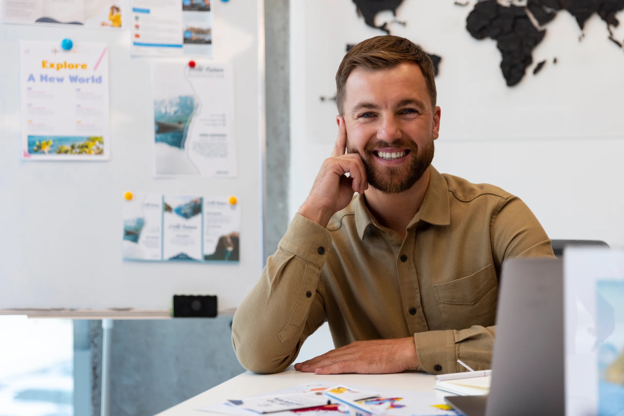 Consultor de agencia de marketing digital Google Ads sonriendo en oficina con pizarra y mapa del mundo al fondo