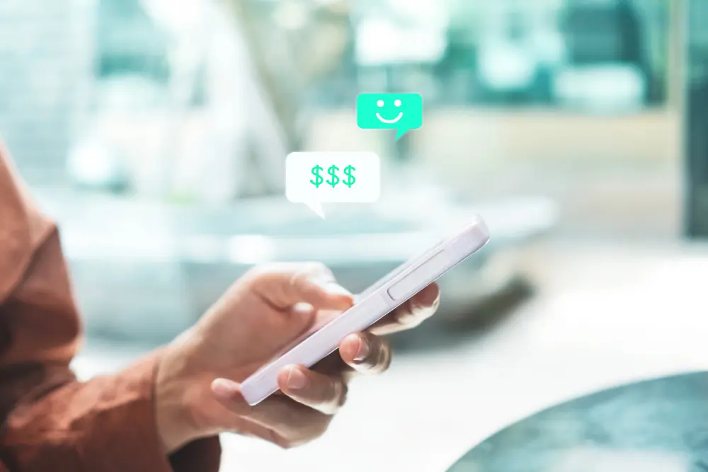 Manos usando teléfono con icono de dólar en chat, CRM para WhatsApp para cobros y ventas.